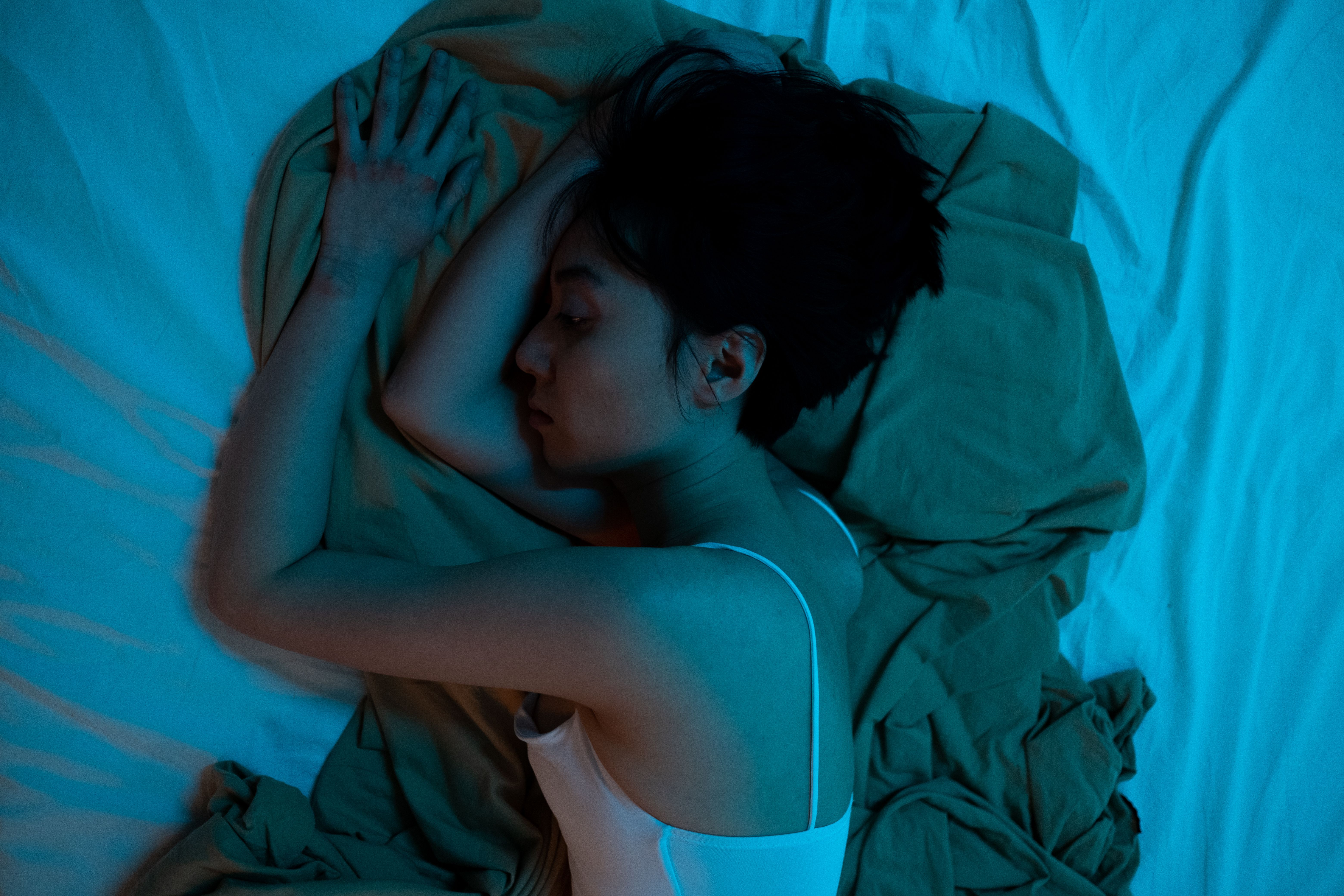 어두운 침실에서 눈을 뜬 채 움직이지 못하고 공포에 질린 사람의 모습, 수면 마비의 심리적 상태를 표현