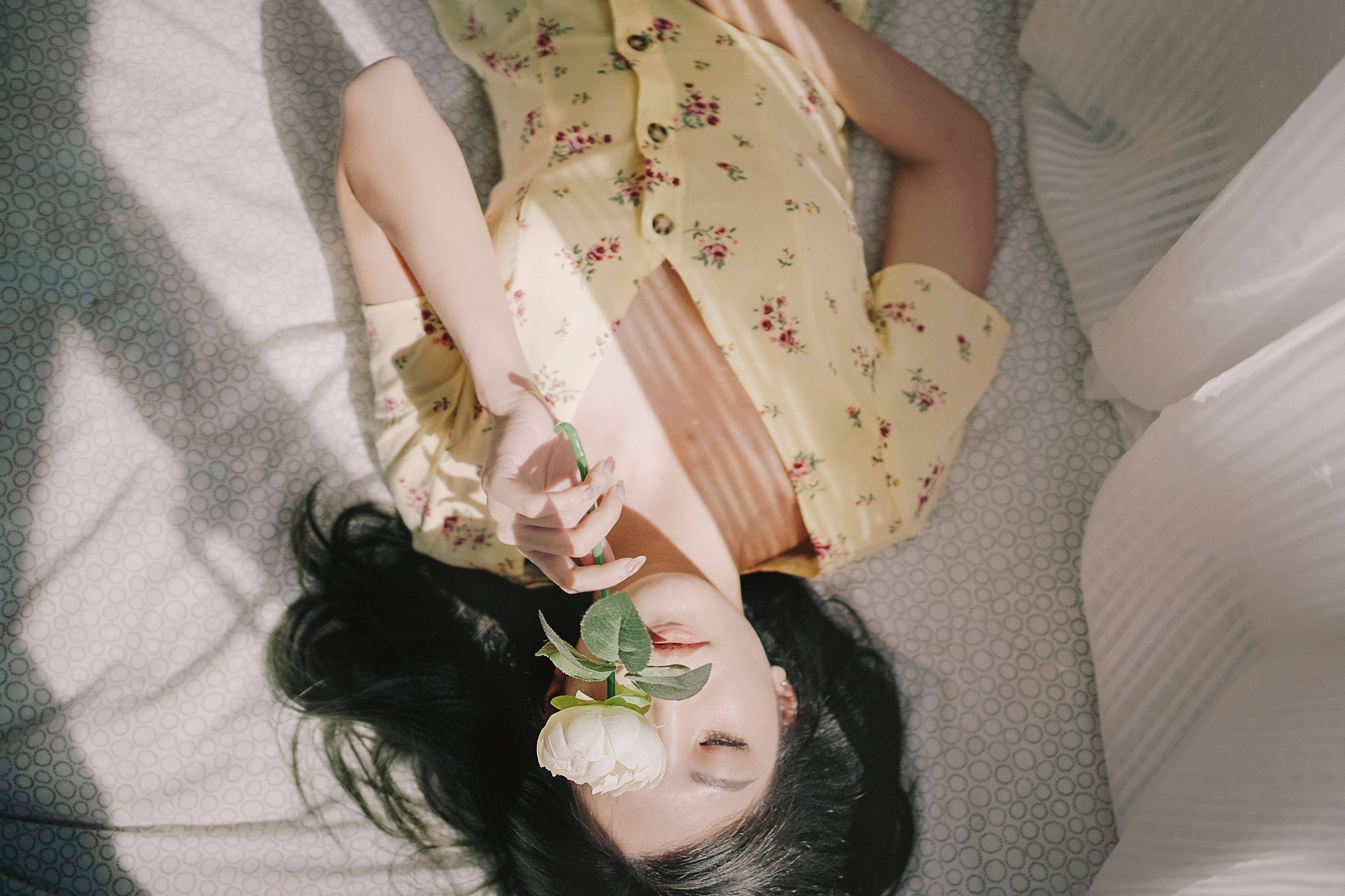 한 사람이 피어나는 꽃 한 송이를 조심스럽게 들고 있는 꿈결 같은 장면. 내면의 감정과 성찰을 표현