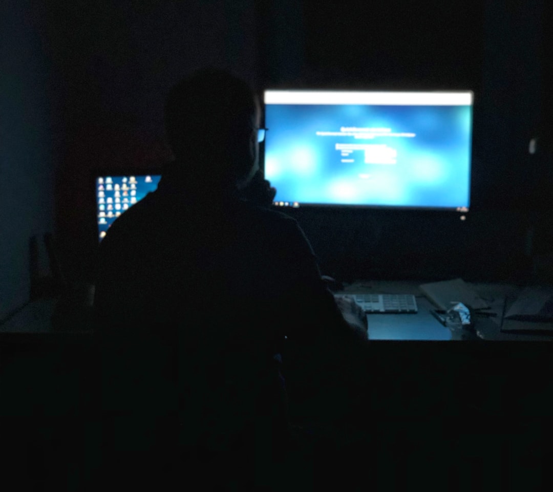 어두운 방에서 디지털 화면에 둘러싸여 머리를 감싸고 있는 사람, 현대인의 스트레스와 디지털 피로를 상징